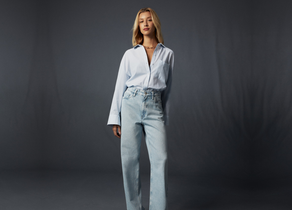 modelo posando com calça jeans wide e camisa 