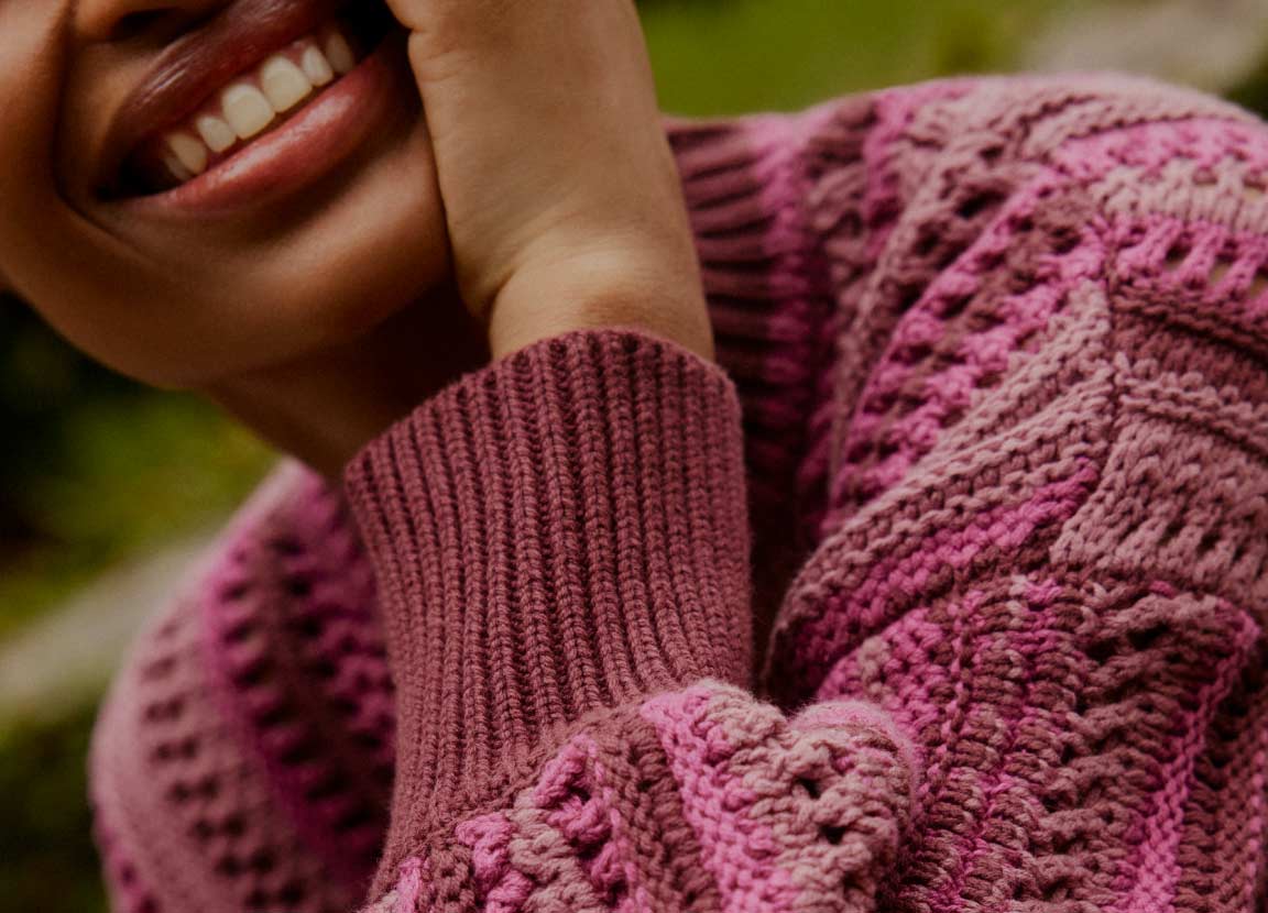modelo com blusa tricot rosa com mão no rosto