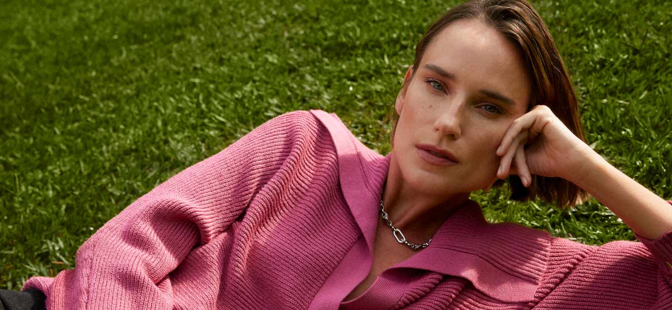 mulher deitada na grama com blusa de trict inverno rosa