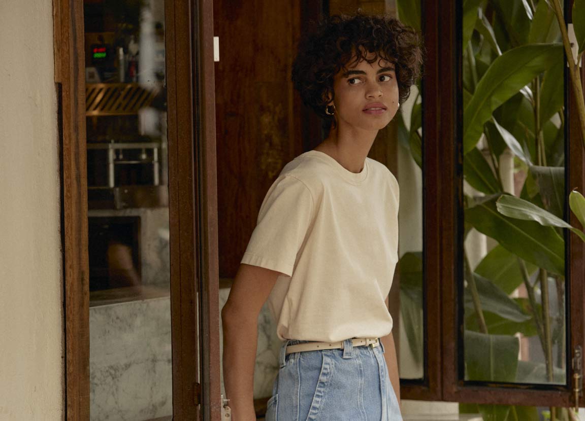 modelo com camiseta bege representando o que não pode faltar no guarda-roupa